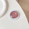 Macro shot of minimalist round crystal glass magnetic phone grip in elegant rose pink - Brown