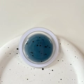 Detail view of round MagSafe phone stand with dark blue glitter and black speckle texture - Magnetic Morandi Ink Splash Blue Grey