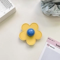 Macro shot of yellow leather flower phone grip with blue center on white marble table - (Clear Stand) 3D Leather Flower - Yellow