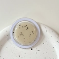 Close-up of translucent facial cream with botanical particles in a glass jar - Magnetic Morandi Ink Splash Milky Grey