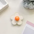 Detail of flower-shaped phone grip with white faux leather petals and orange resin core - (Clear Stand) 3D Leather Flower - Off-White/Orange