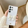 Detailansicht einer Samsung S24 Ultra Hülle mit Glitzer und weißer 3D-Schleife in der Hand - Samsung A14 / Glitzer Creme Künstliche Perle Schleife Stil