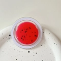Macro shot of watermelon lip balm with seeds texture on a white ceramic tray - Magnetic Morandi Ink Splash Coral Red