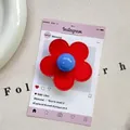 Detailed view of flower phone grip with red stitched petals and blue round center - (Magnetic) 3D Leather Flower - Red