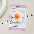 Detail of flower-shaped phone grip with cream petals and orange center on a card - (Magnetic) 3D Leather Flower - Off-White/Orange