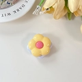 Detailed view of yellow flower phone grip with glossy resin finish on beige surface - Yellow