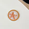 Primer plano del soporte móvil de estrella de mar con purpurina y detalle de perla - Estrella de Mar Perlada Redonda Magnética / Naranja