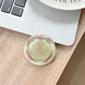 Macro detail of a heart-shaped matte green phone grip with Good Luck pink text - Magnetic Sandwich Heart / Jasmine Green