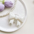 Detail of white glitter 3D bow phone socket stand on a ceramic plate with decor - Large Bow Stand-Pearl-White