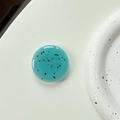 Macro detail of round light blue terrazzo phone grip with black speckled pattern texture - Deep Lake Blue