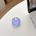 Macro detail of lavender round crystal glass phone grip with glossy finish on white desk - Purple