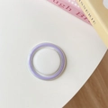Dettaglio del supporto per telefono circolare color lavanda su superficie minimalista - Bianco + Viola