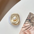 Detail of matte gold oval phone socket with a large pearl center on a white surface - Magnetic Pearl Swirl Style / Matte Gold