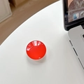 Detailed view of a bright red crystal glass phone socket stand on a white desktop - White Stand / Red