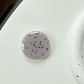 Macro detail of round minimalist phone grip with speckled stone texture on clean background - Coffee Grey