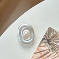 Macro shot of an oval matte silver metal phone socket with a white pearl inlay detail - Transparent Pearl Swirl Style / Matte Silver