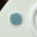 Macro shot of minimalist blue phone grip with black ink splatter and glossy finish - Blue