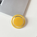 Macro top view of yellow magnetic circular phone grip on silver laptop surface - Turmeric