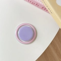 Detail shot of a candy-colored round collapsible phone grip with pastel pink and purple finish - Purple + Pink