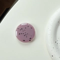 Macro shot of minimalist lavender resin phone grip with artistic black speckle patterns - Mauve