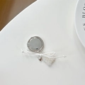Detalle de dijes de corazón de perlas y metal plateado en un soporte de lazo blanco - Estilo de Lazo de Corazón Blanco Plateado