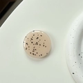 Minimalist round phone grip featuring beige resin surface with modern black spotted pattern - Milk Tea