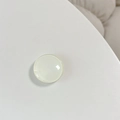 Macro detail of clear round crystal glass phone grip showing smooth polished surface - Beige