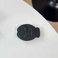 Macro shot of black leather fish phone grip with embossed smiley face and texture - Leather Taiyaki / Black
