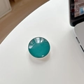 Detail of teal crystal glass phone socket grip on white desk with laptop background - Dark Green