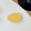 Macro view of yellow leather fish phone stand with embossed face and stitched edge - Leather Taiyaki / Yellow