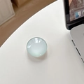 Close-up of translucent light blue round phone socket on a white minimalist desktop - Milky Green