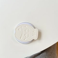 Dettaglio del supporto per telefono in pelle crema a forma di pesce con texture - Bianco