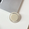 Close-up of a minimalist circular magnetic phone stand on a clean white desk setup - Milky Grey