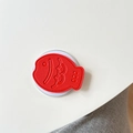 Dettaglio del supporto per telefono taiyaki rosso con cuciture sottili e scaglie a rilievo - Rosso