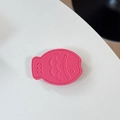 Macro shot of pink fish-shaped leather phone grip showing lychee texture and embossed detail - Leather Taiyaki / Rose Red