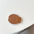 Close-up of brown fish-shaped leather phone stand with stitching on a white background - Brown