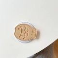 Detailed view of fish-shaped leather phone grip with scale texture on a white surface - Khaki