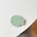 Detail of light green fish-shaped leather phone grip with lychee texture and stitching - Green
