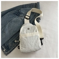 Close-up of white nylon chest bag with wrinkled texture and round metal logo on denim jacket - White
