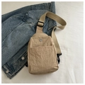 Detail of khaki waterproof nylon sling bag with metal M logo and woven strap on denim - Khaki