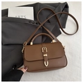 Detalle de bolso vintage de cuero sintético marrón oscuro con hebilla dorada y asa - café