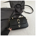 Detalle de bolso negro con hebilla dorada sobre el fondo de una chaqueta gris - Negro