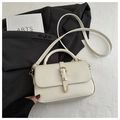 Detalle de bolso de cuero blanco crema con hebilla dorada sobre fondo de chaqueta negra - Blanco