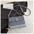 Detail of blue-gray crossbody bag featuring woven texture and silver horseshoe buckle - Blue