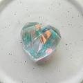 Close-up of heart-shaped holographic crystal phone grip on a white patterned ceramic plate - Geometric Heart (Large) / Blue