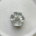 Close-up of clear cat paw phone grip with embossed heart detail on white tray - Cat Claw (Glossy) / Tin Foil Pattern