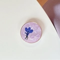 Détail d'un support de téléphone rond avec fleur séchée bleue et nœud en perles en résine - Fleur de Perle à Cercle Doré / Violet Scintillant