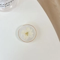 Macro shot of circular resin phone grip featuring white dried flower and gold rim - Transparent Stand - Gold Ring Glitter Swallow - White