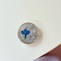 Gros plan d'une fleur séchée bleue avec nœud en perles dans une résine époxy pailletée - Fleur de Perle à Cercle Doré / Gris Éclair Nuage