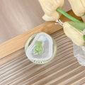 Nahaufnahme einer grünen Bären-Handyhalterung auf Glastisch mit Tulpen im Hintergrund - Magnetischer Stil (Grün)